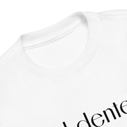 Chunky Deli product image: White "Al Dente" kids' t-shirt laid flat on the ground with the graphic text "Al Dente" across the front. This is a close up shot of the neckline. 