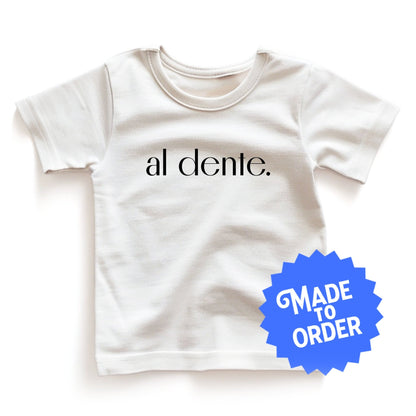 Chunky Deli product image: White "Al Dente" kids' t-shirt laid flat on the ground with the graphic text "Al Dente" across the front and a "Made to Order" sticker beside it.