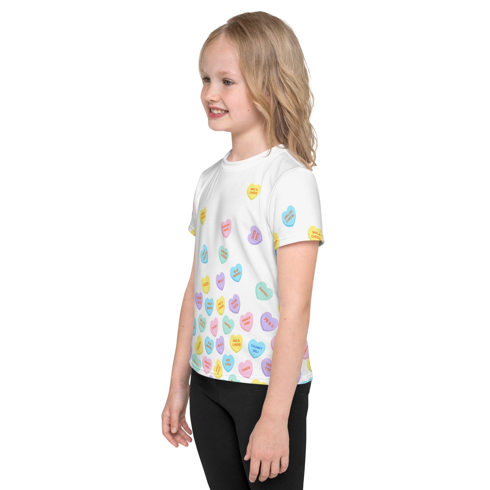  Chunky Deli product image: Left side view of a girl wearing the "Candy Hearts" t-shirt (white with colorful candy hearts featuring food illustrations), showing the design on the side of the shirt.