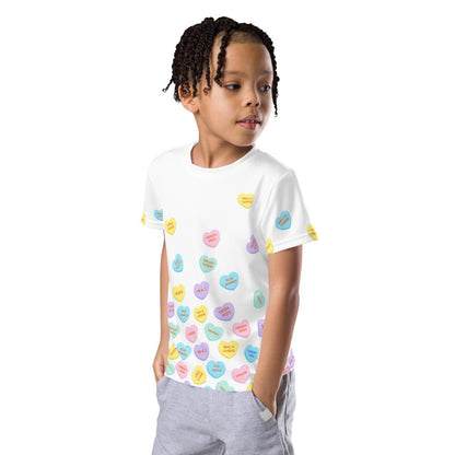 Chunky Deli product image: Boy wearing the "Candy Hearts" t-shirt (white with colorful candy hearts featuring food illustrations), standing with his hands in his pockets against a white background.