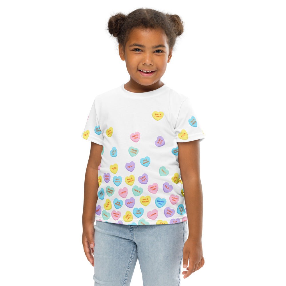 Chunky Deli product image: Close-up of a smiling girl wearing the "Candy Hearts" t-shirt (white with colorful candy hearts featuring food illustrations), wearing jeans, against a white background.