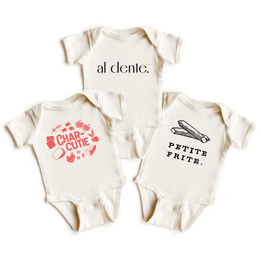 Chunky Deli product image: Three natural-colored baby onesies fanned out on a white background, each with a different graphic design: "Charcutie," "Al Dente," and "Petite Frite." All are 100% cotton with three-snap closures and envelope shoulders.