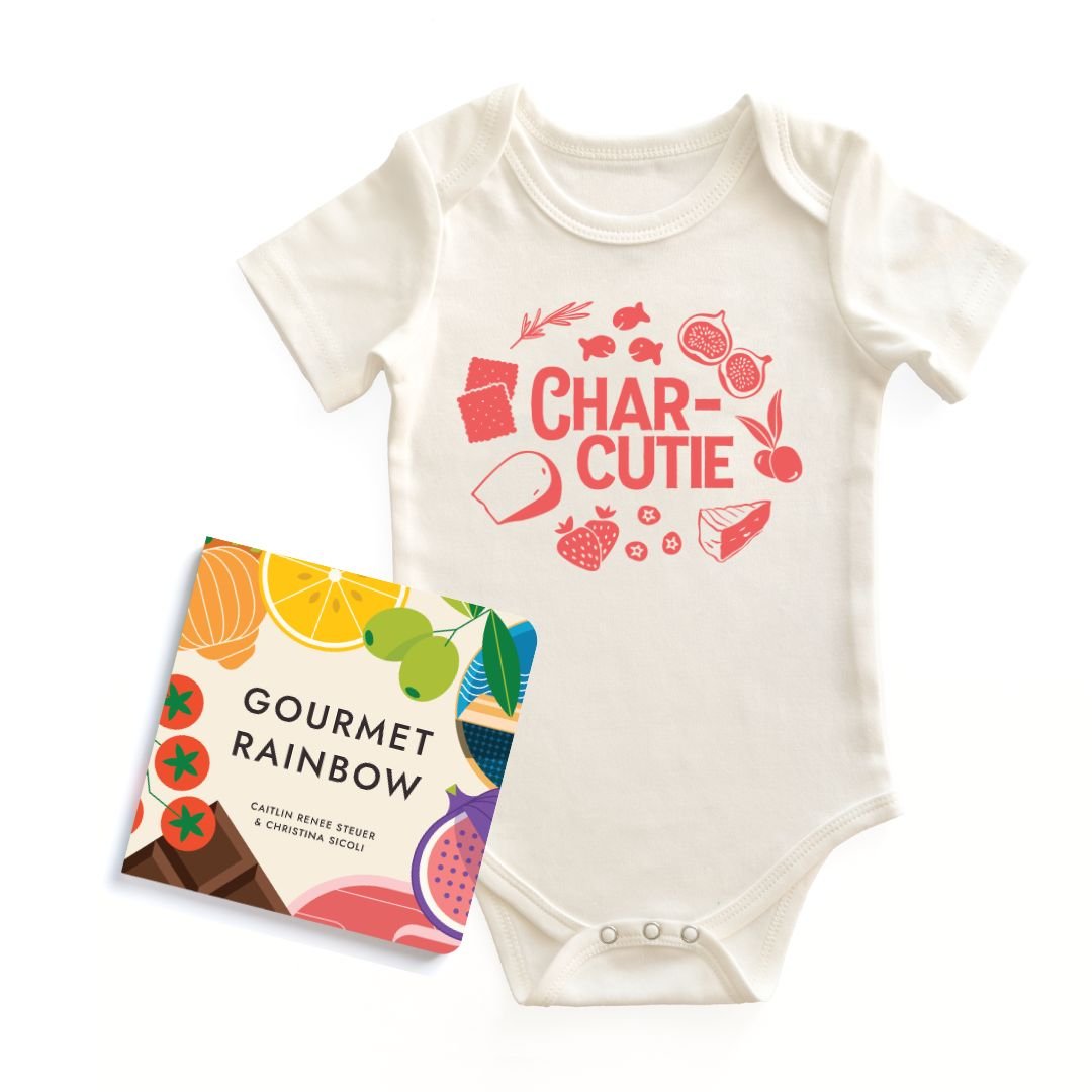 Flat lay of the "Gourmet Baby Starter Pack" including a natural cotton "Char-cutie" baby onesie bodysuit and the "Gourmet Rainbow" board book on a white background. Chunky Deli product display.