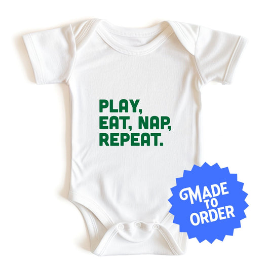 Chunky Deli product image: "Play Eat Nap Repeat" baby onesie (100% cotton, natural color) laid flat on a white background, showcasing the envelope shoulders, short sleeves, three-snap closure, and the text "Play Eat Nap Repeat" stacked vertically in green