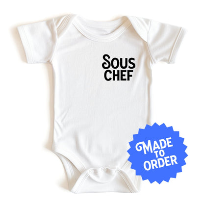 Chunky Deli product image: White-colored "Sous Chef" onesie (100% cotton) laid flat on a white background, showcasing the envelope shoulders and three-snap closure.