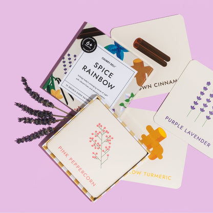 Chunky Deli product image: "Spice Rainbow" art cards box open on a purple background, with spice cards scattered around, showcasing illustrations and sight words. Real lavender sprigs are included to highlight the connection to the lavender card and its e