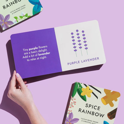  Hand holding the "Spice Rainbow" board book open to the purple lavender page, showcasing the illustration and rhyme. Purple background with two additional books in the background. Chunky Deli product image.